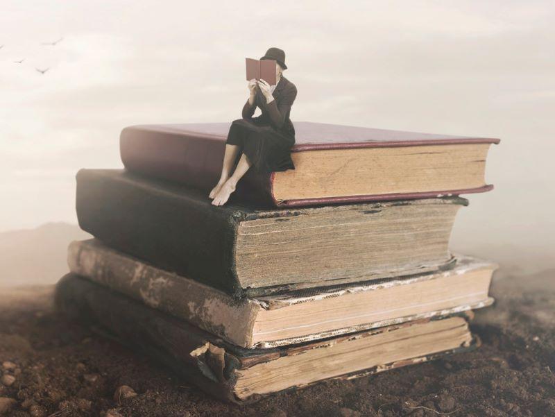 Woman perched on a pile of old books representing the traditional view of history teaching