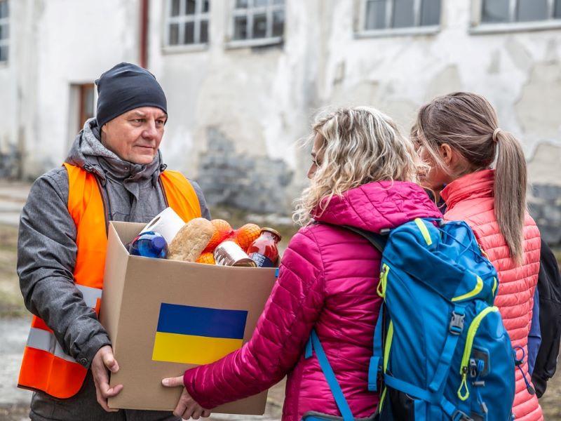 Image showing a box of essential items being handed to two Ukrainian women