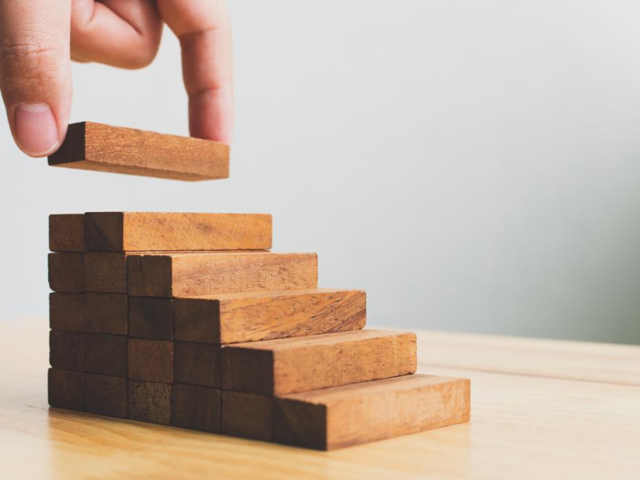 Building blocks ascending as a disembodied hand stacks them on top of one another