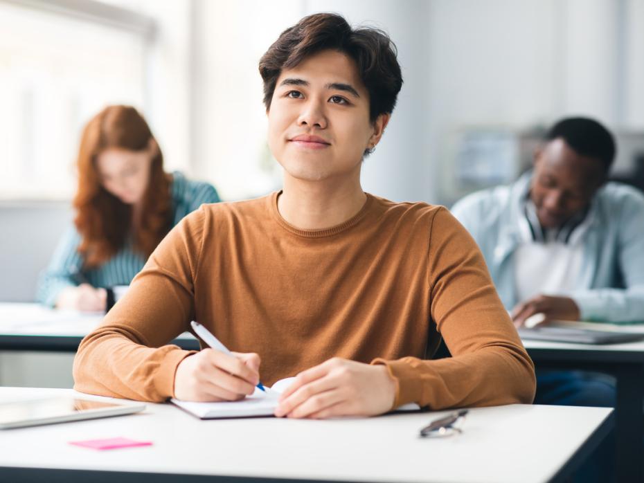 Student sat at a desk listening to an off-screen teacher in cass 