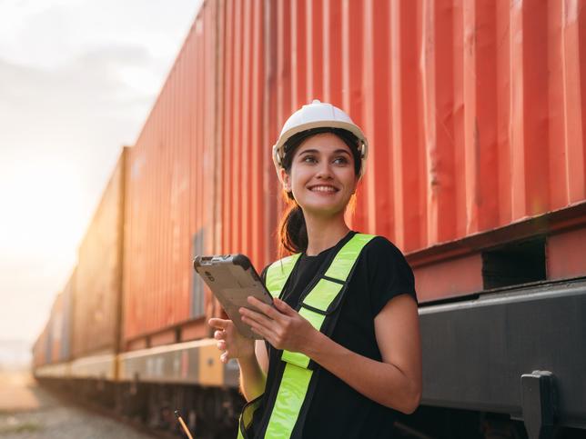 A young woman in a hard hat checks inventory on a tablet