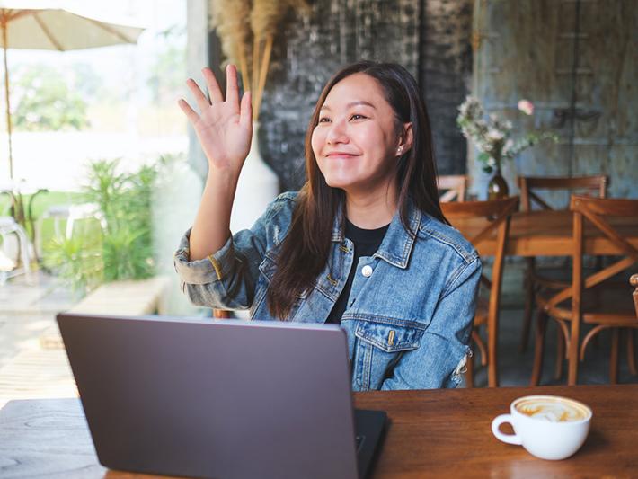 Young Asian woman greeting friend at cafe