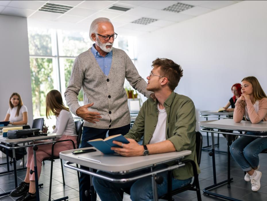 A lecturer speaking to a student at their desk