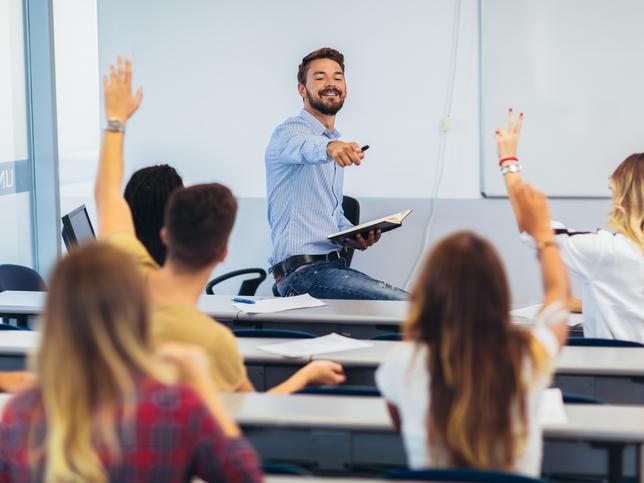 A lecturer takes questions from students with raised hands