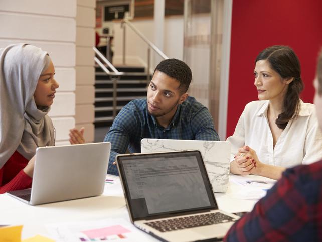 Students talk to their teacher round a table