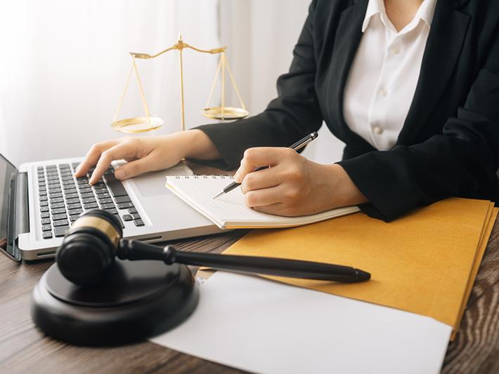 young woman working at laptop with gavel in foreground