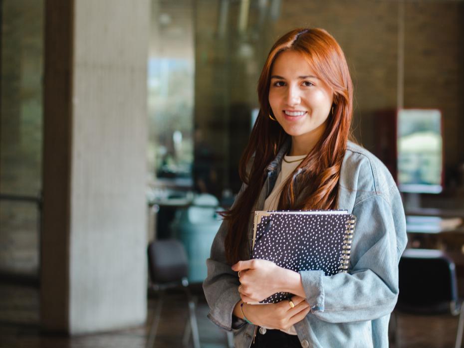 Student holding her books smiling to camera