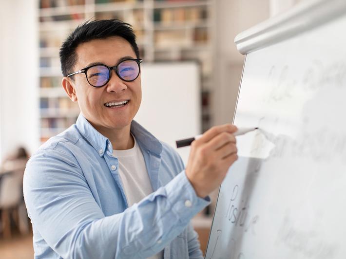 Smiling Chinese college tutor at whiteboard