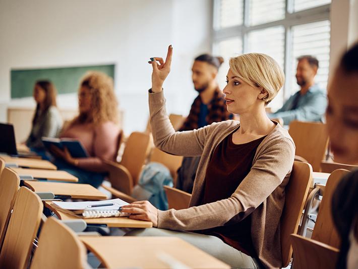 Mature age female student with hand up in lecture theatre