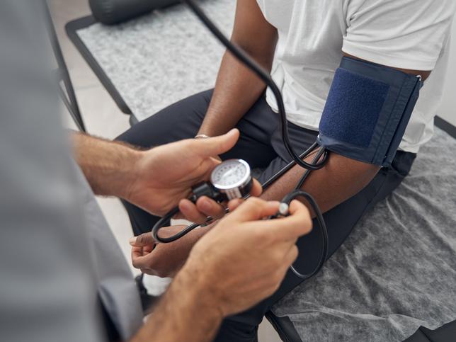 A Black man has his blood pressure taken