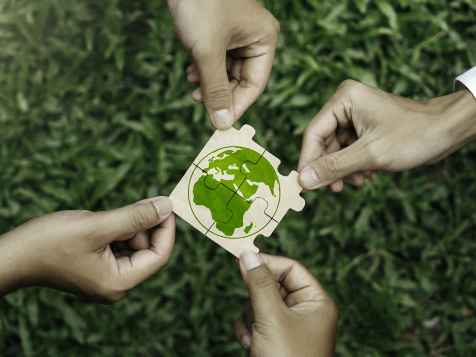 Hands holding together a jigsaw depicting the Earth