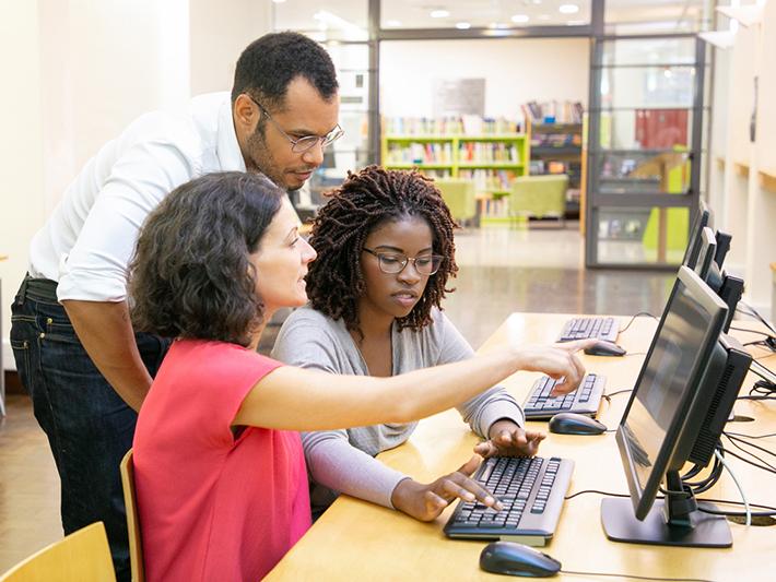 Multiracial group of three people looking at a computer