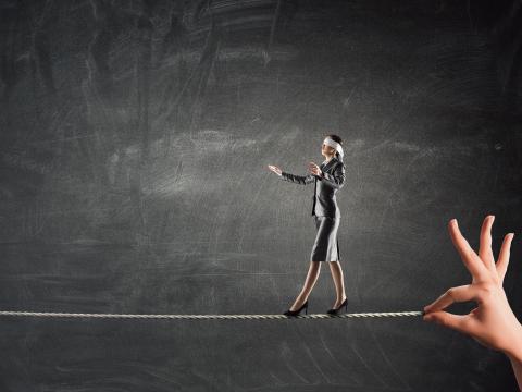 A woman walking blindfolded along a tightrope