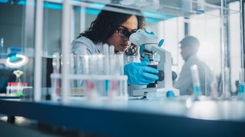 Researcher looking through a microscope in a lab