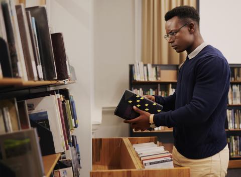 Male librarian sorting out books