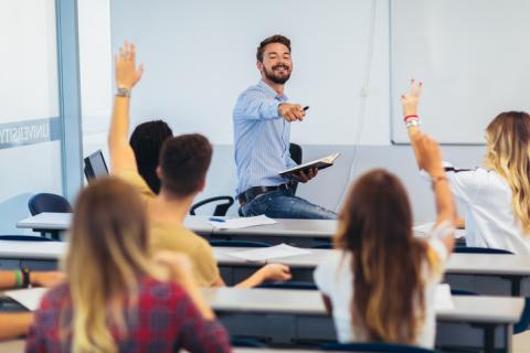 A lecturer takes questions from students with raised hands