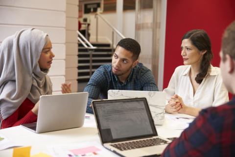 Students talk to their teacher round a table