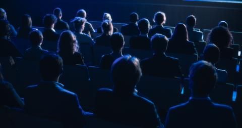 An audience in a darkened lecture hall