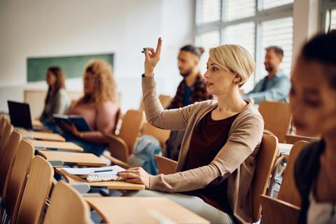 Mature age female student with hand up in lecture theatre