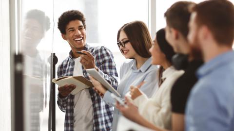 Students laugh together while working on a whiteboard