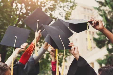 Students holding their graduation caps in the air