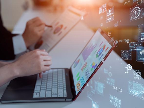 Hands at laptop surrounded by cloud of tech-related icons