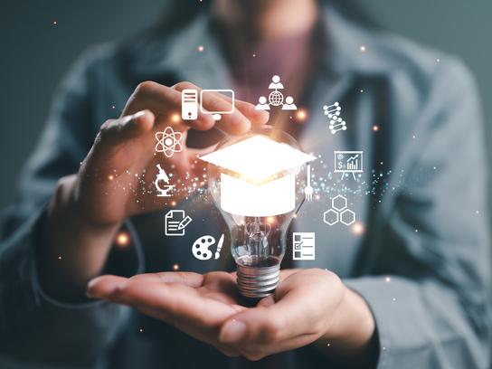 Woman holding light bulb with symbols of academic fields surrounding it