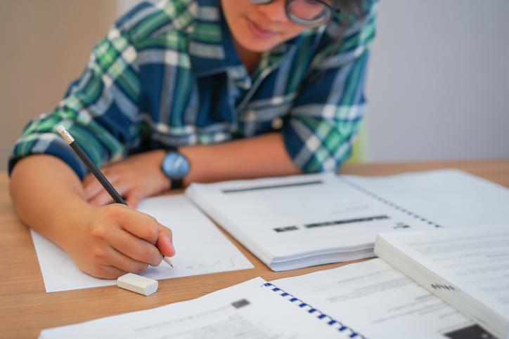 A student in glasses works at a desk