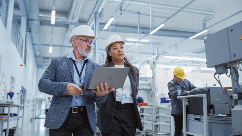 Two people in hard hats walk through a lab