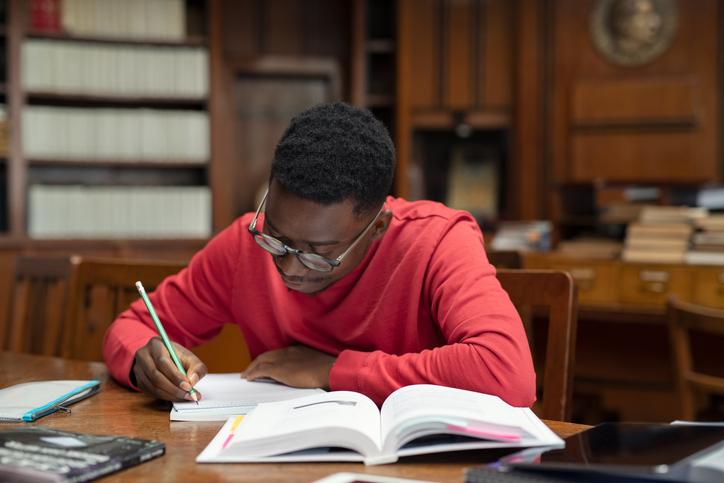 A student in the library makes notes