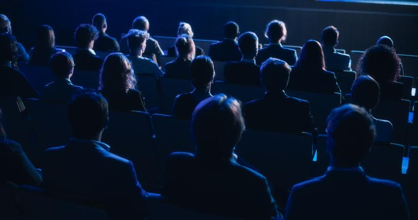 An audience in a darkened lecture hall