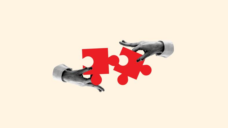 Two hands fit jigsaw puzzle pieces together