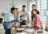 A group of people laugh over a sheet of paper in a well-lit office