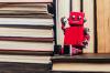 A red toy robot sits on a pile of books