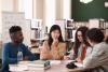 A group of students converse over a table